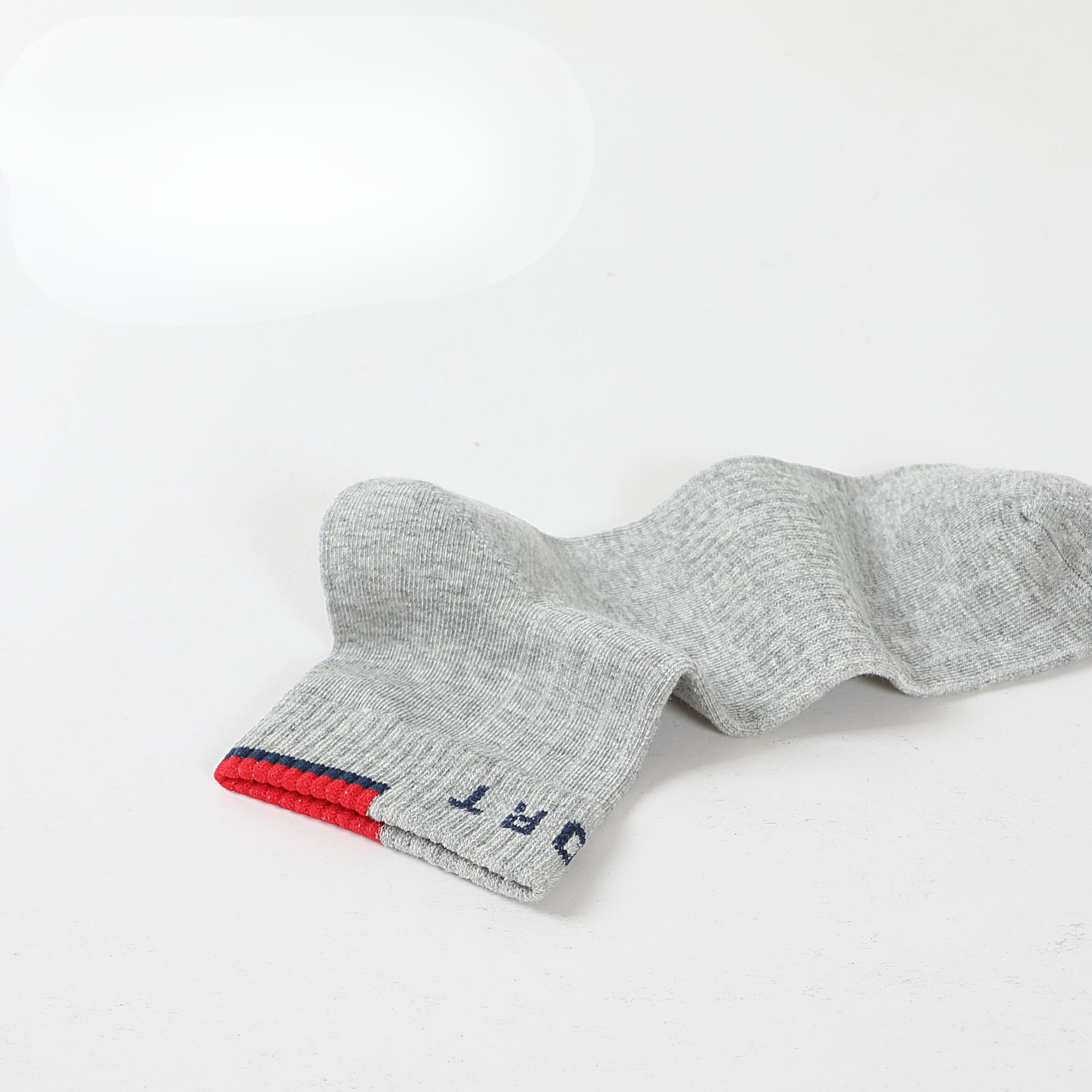 A single gray ankle sock laid flat, highlighting the ribbed design and reinforced cuff