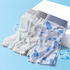 Three pairs of men's underwear in blue and white patterns with gray elastic waistband, displayed on blue background