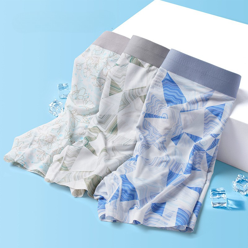 Three pairs of men's underwear in blue and white patterns with gray elastic waistband, displayed on blue background