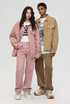 A woman and man standing together modeling coordinated outfits with pink and tan denim jackets, wide-leg pants, and graphic tees