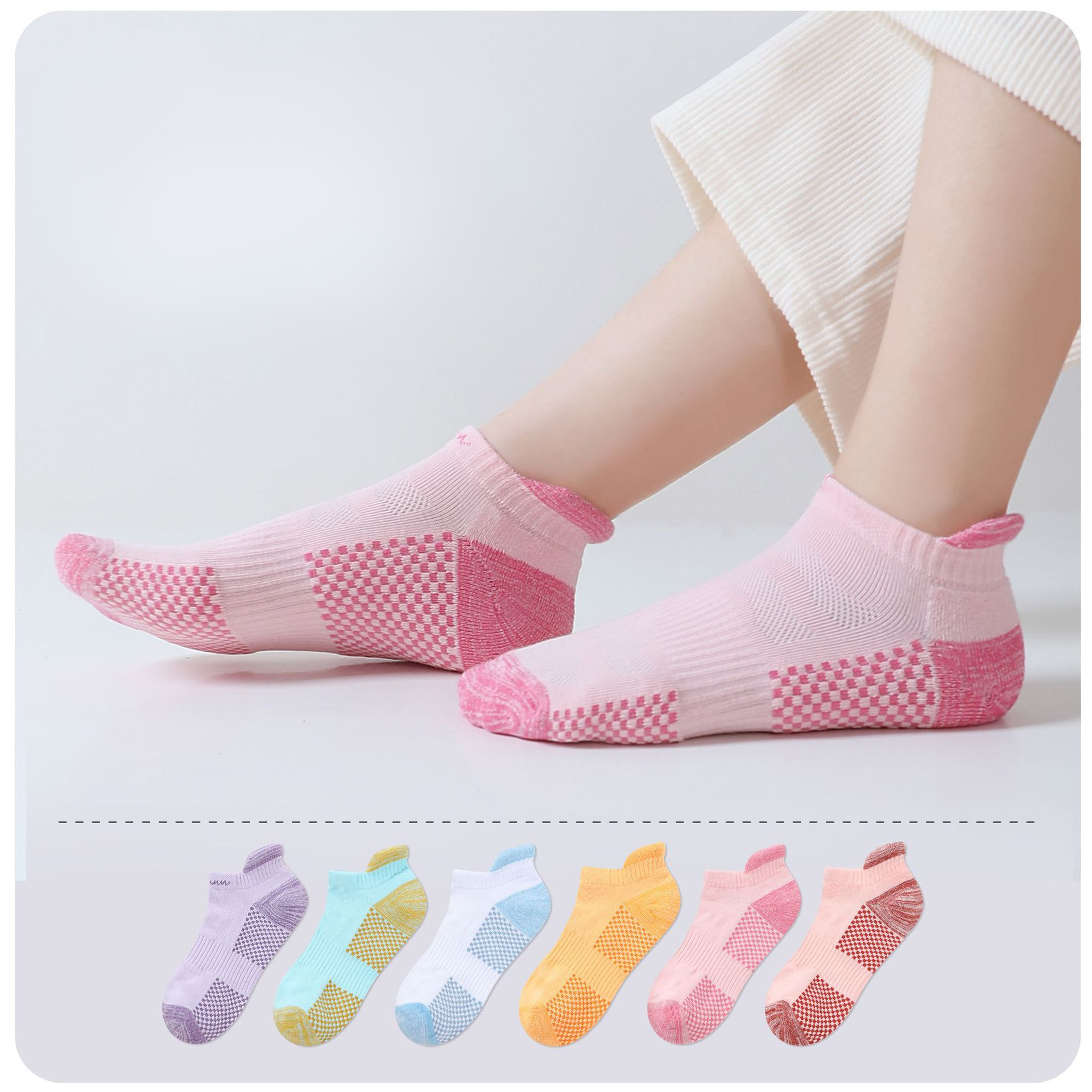 Pink athletic ankle socks worn on feet with cream pants, featuring checkered cushion zones and moisture-wicking fabric. Six pastel colored sock options displayed below