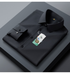 A folded black dress shirt displayed on dark gray surface. Sleek collar detail and buttoned placket visible with brand tag