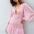 Woman wearing a pink dress with bell sleeves.