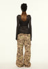 Back view of model wearing black sheer ribbed top showing fitted silhouette and long sleeves.