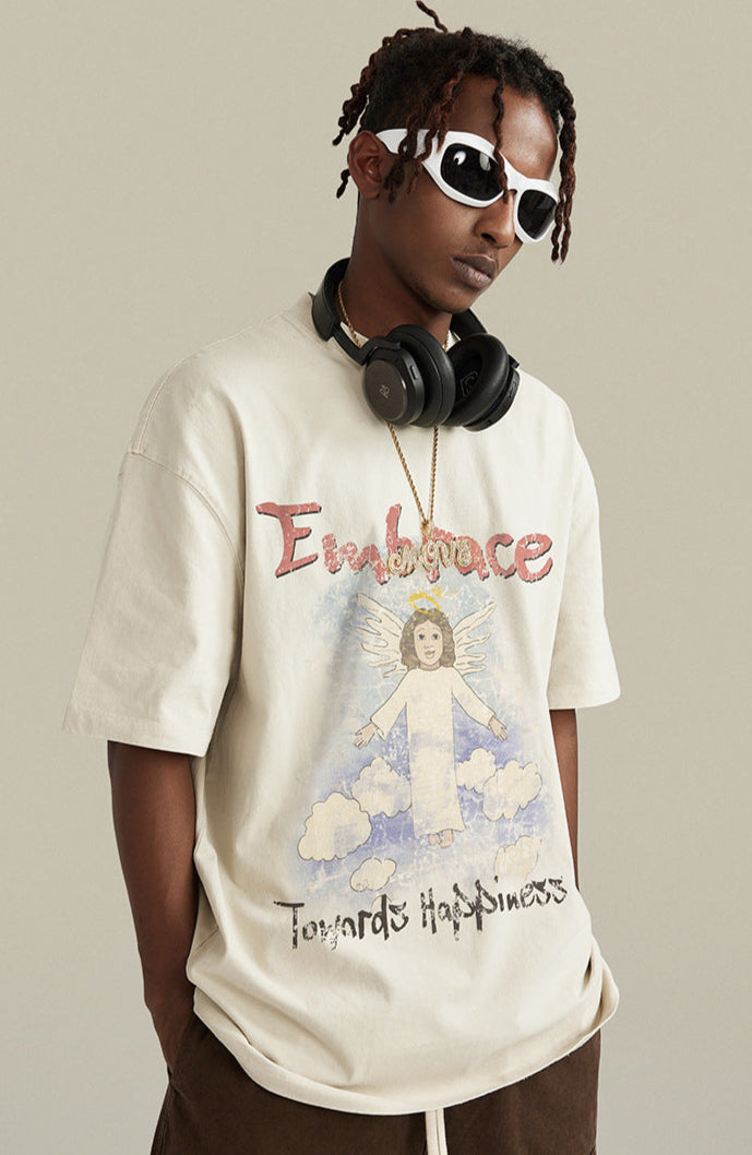 Man wearing angel tee gestures with hand forward, styled with headphones and sunglasses