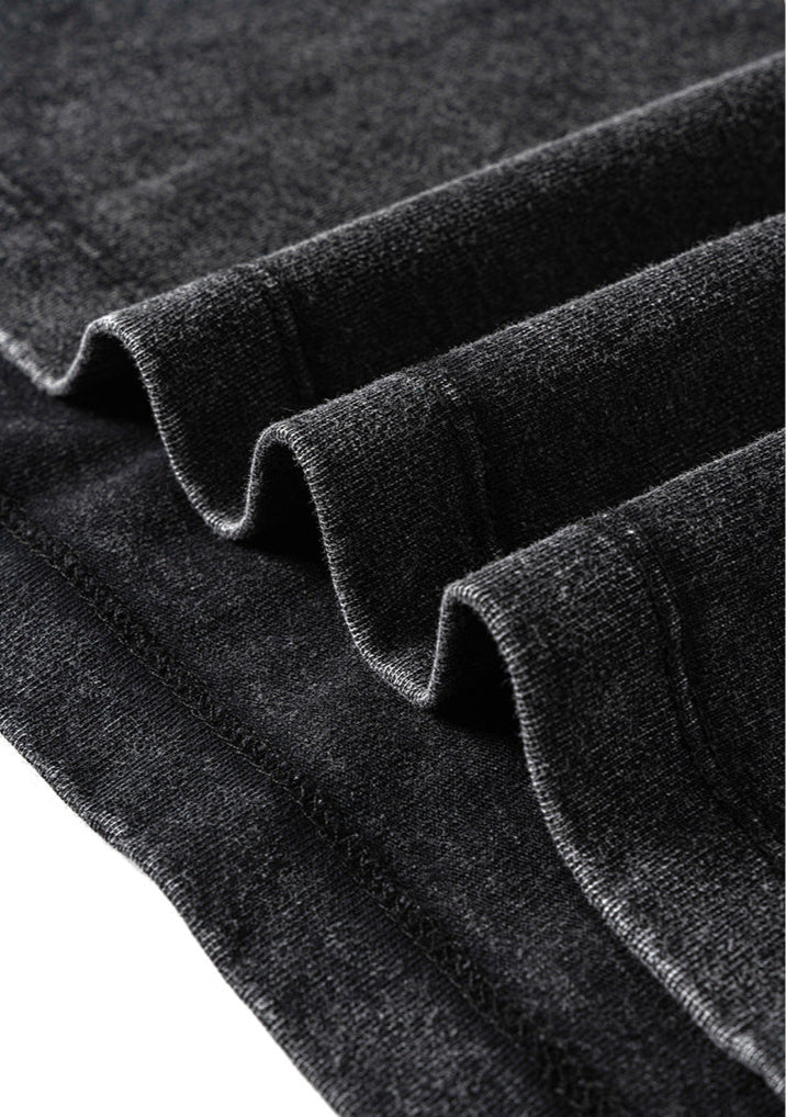 Folded fabric layers of black tee showcasing texture and edge stitching.


