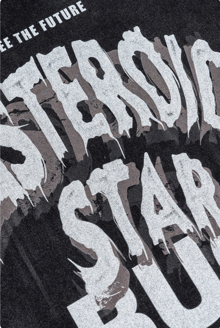 Tight crop of distressed “Asteroid Star Bug” text print on black tee fabric.