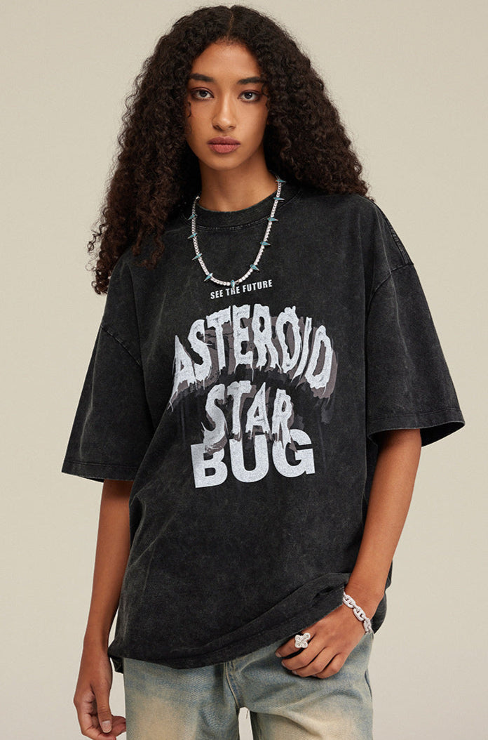 Close-up of model in oversized washed black tee with bold white graphic lettering.