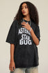 Model looks ahead in black graphic T-shirt styled with faded denim and sneakers.