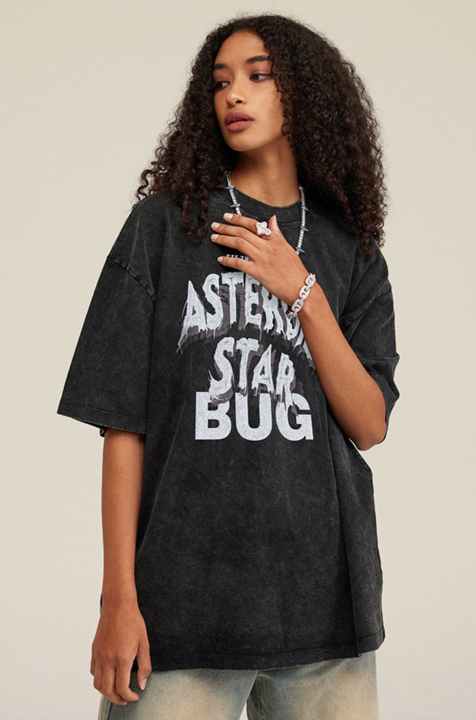 Model looks ahead in black graphic T-shirt styled with faded denim and sneakers.