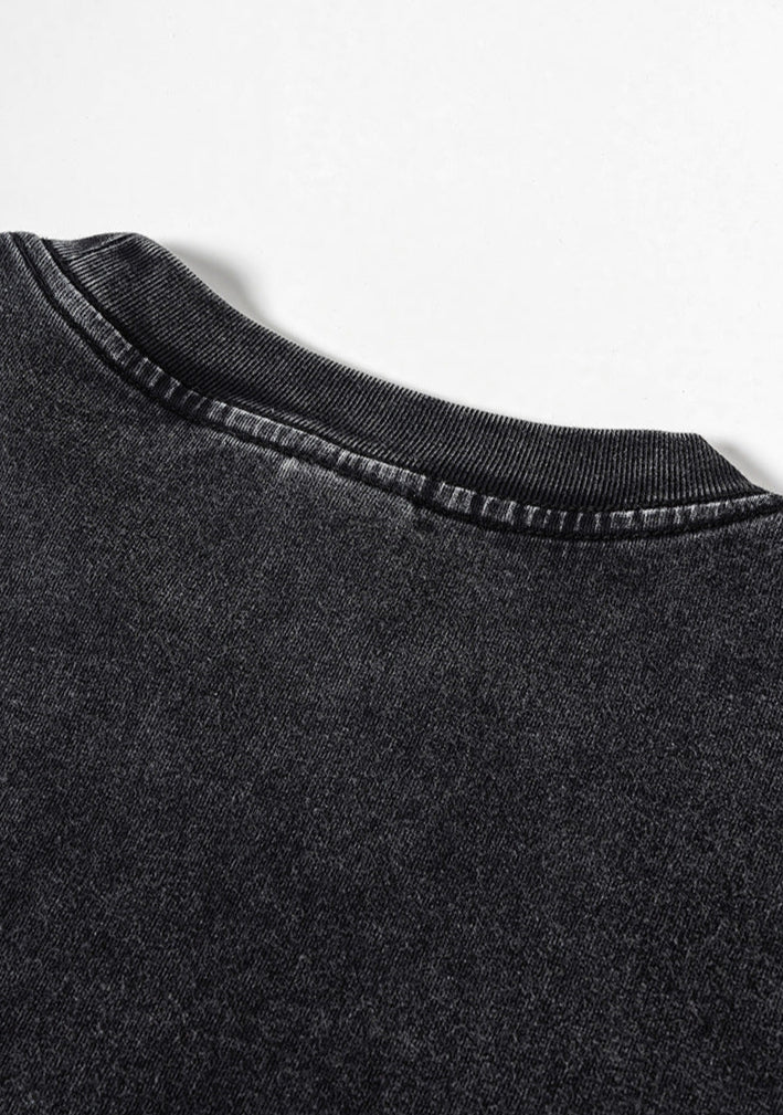 Back neckline detail on washed black tee with ribbed collar and fade effect.