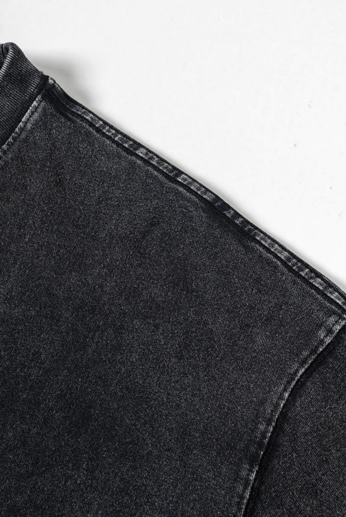 Shoulder seam detail on washed black tee against white background.