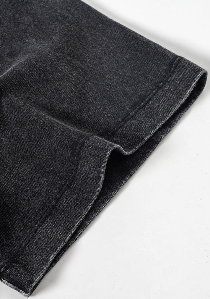 Folded sleeve hem detail on black tee with visible twin-needle stitching.