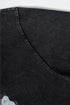 Close-up of underarm seam on washed black tee showing curved stitching.
