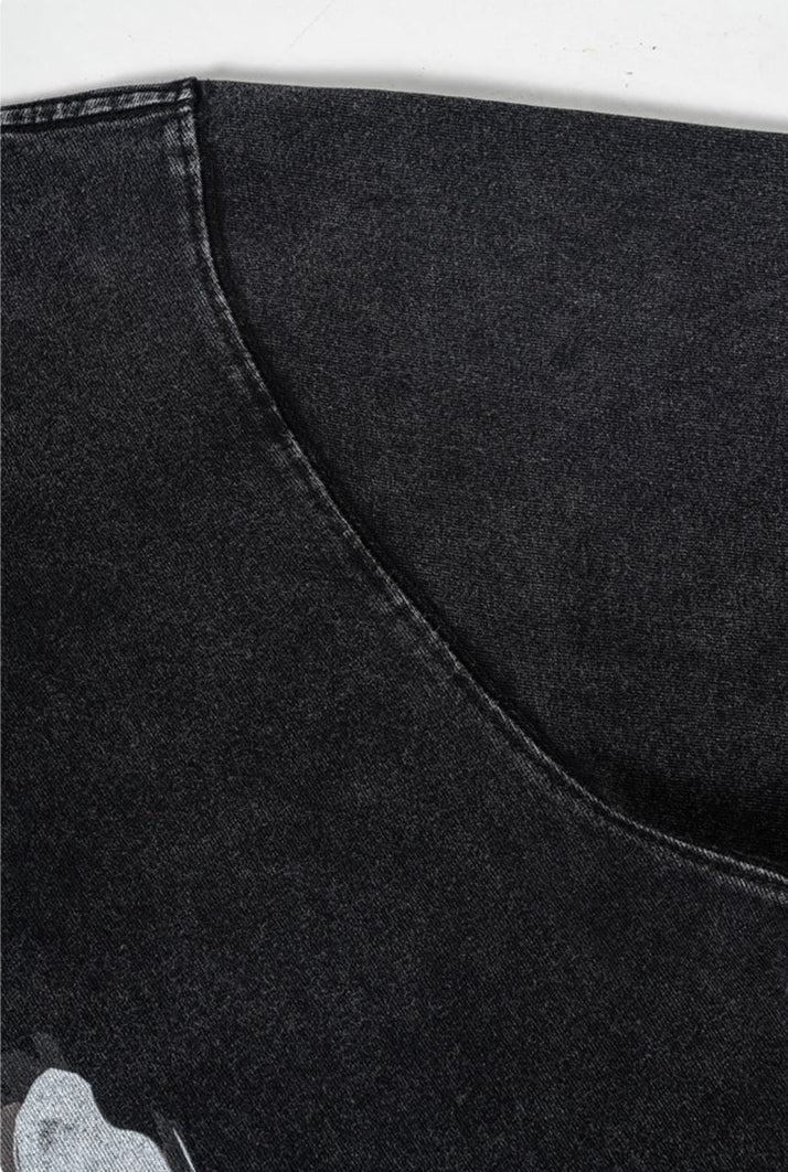 Close-up of underarm seam on washed black tee showing curved stitching.