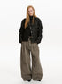 Black cropped button jacket styled with wide gray trousers in a full-length front view.