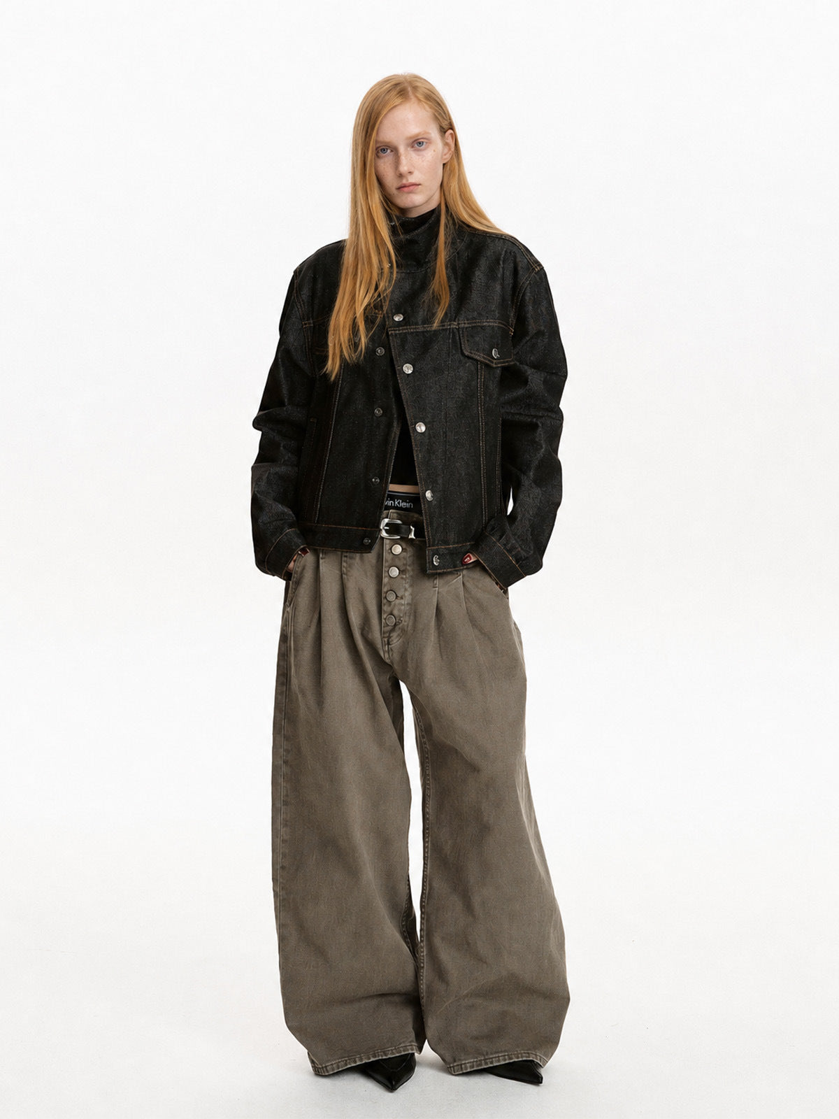 Black cropped button jacket styled with wide gray trousers in a full-length front view.