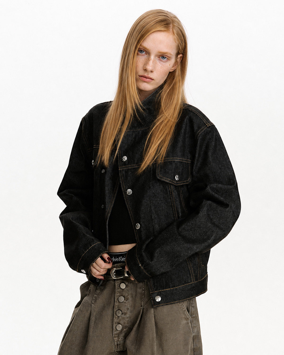 Three-quarter view of black cropped jacket with flap chest pockets and metal buttons.