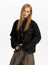 Three-quarter view of black cropped jacket with flap chest pockets and metal buttons.