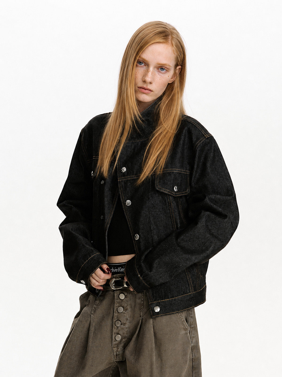 Three-quarter view of black cropped jacket with flap chest pockets and metal buttons.