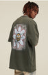 Model turned showing back of tee with white daisy and cartoon face graphic.