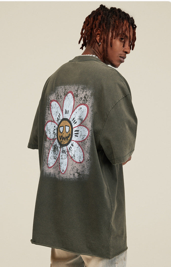 Model turned showing back of tee with white daisy and cartoon face graphic.