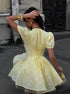 Woman in a yellow dress standing on a street.