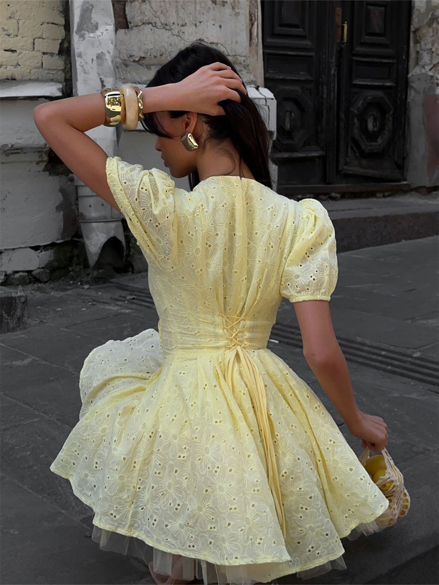 Woman in a yellow dress standing on a street.