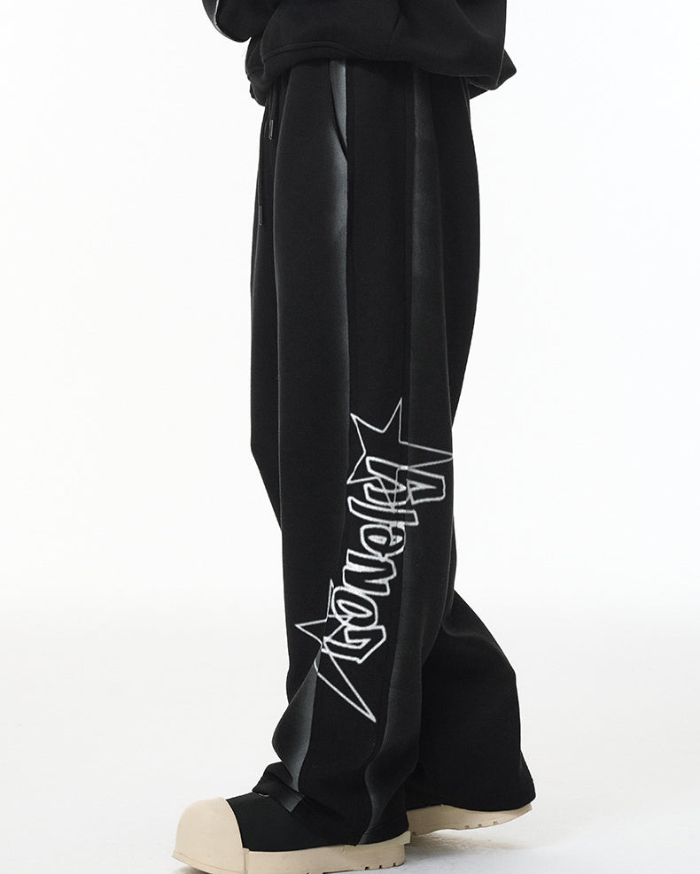 Side view showing vertical “Lonely” graphic on calf of black wide-leg sweatpants.