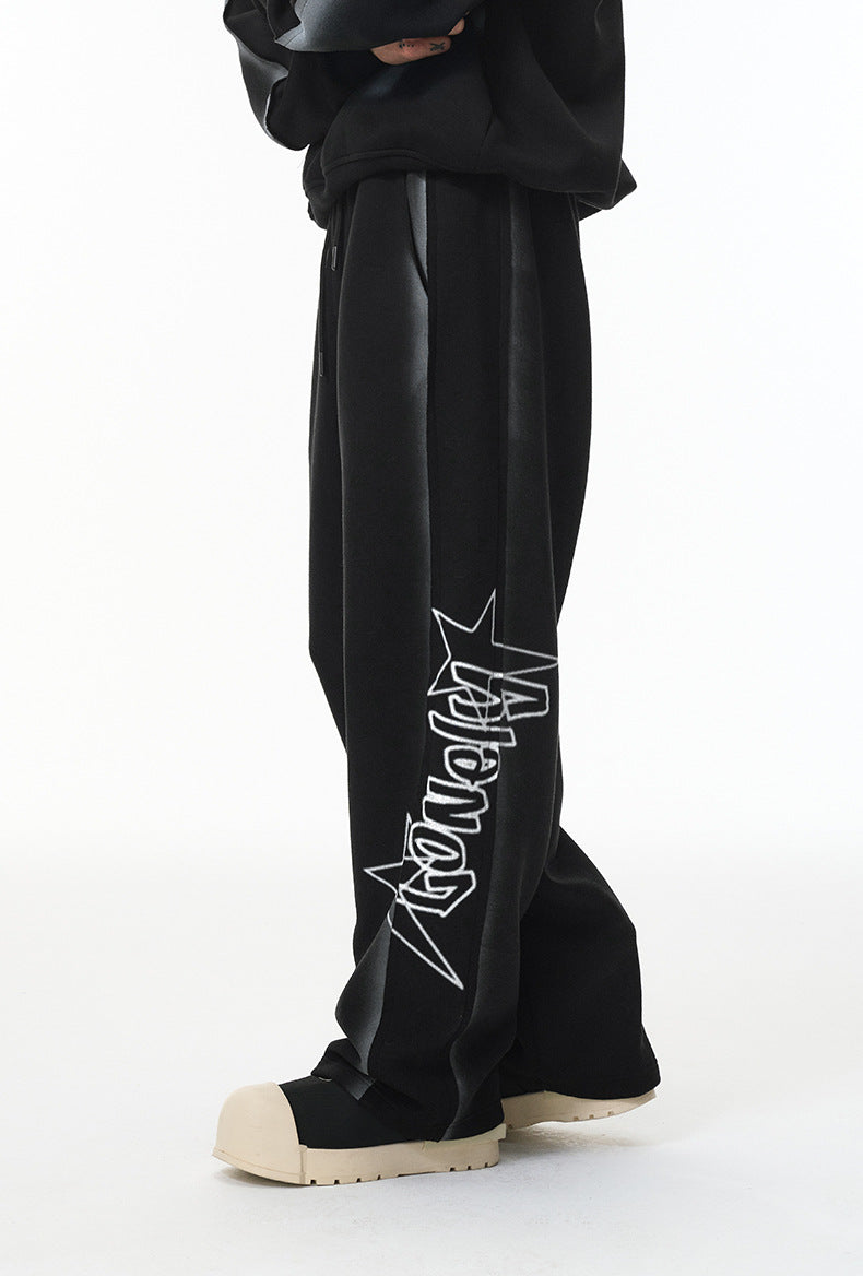 Side view showing vertical “Lonely” graphic on calf of black wide-leg sweatpants.