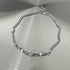 Silver necklace with varied beads and smooth chain on brushed surface.