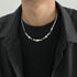 Man wears silver chain necklace with mixed metal beads.