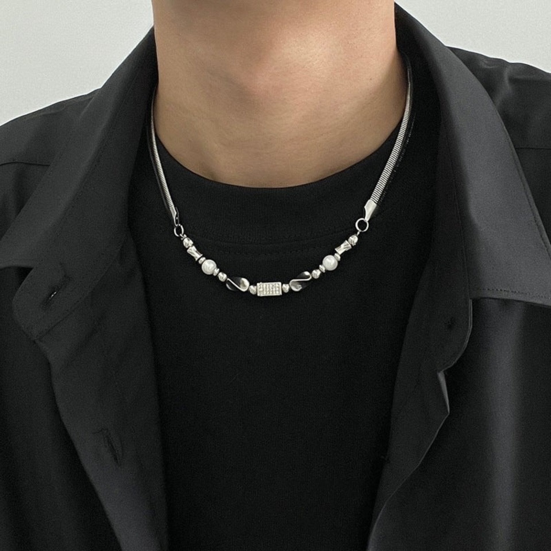 Man wears silver chain necklace with mixed metal beads.