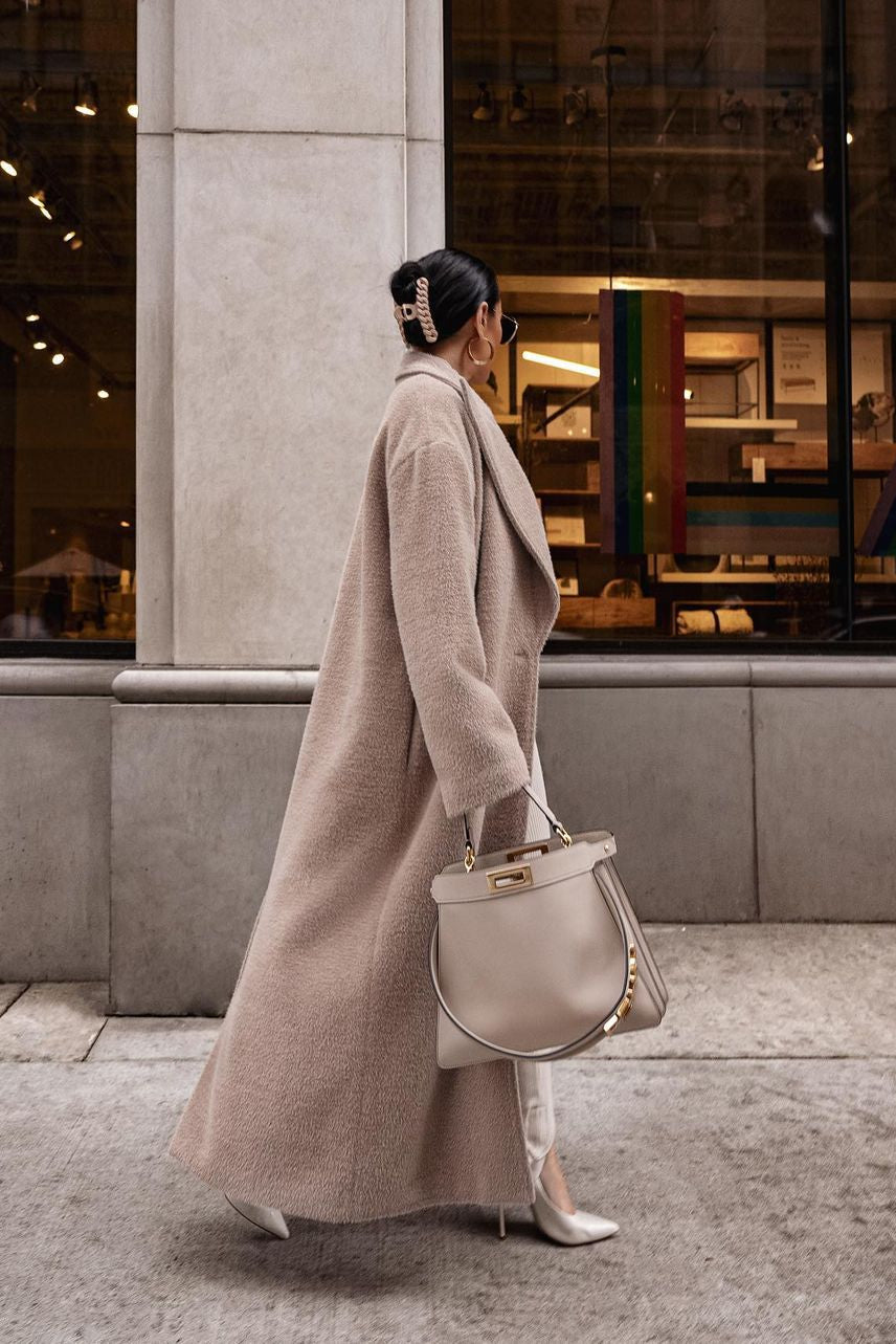 Beige long teddy coat, side sweep in motion, city walkway