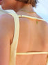 Back detail of beige sleeveless midi dress with simple straps and clean slim silhouette.