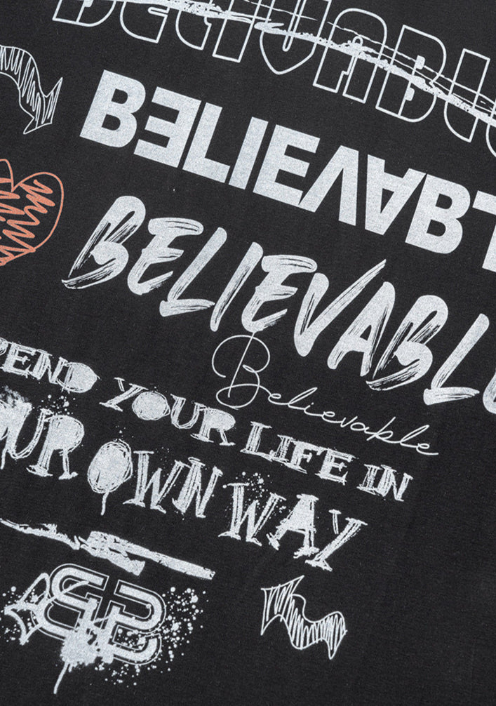 Angled view of layered 'Believable' typography and street-style slogans on black tee.