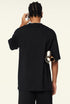 Back of black oversized T-shirt worn by model with rolled posters under arm.