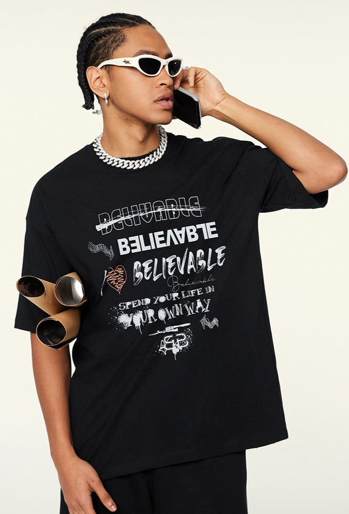 Side view of model in black oversized tee on phone, holding poster tubes.