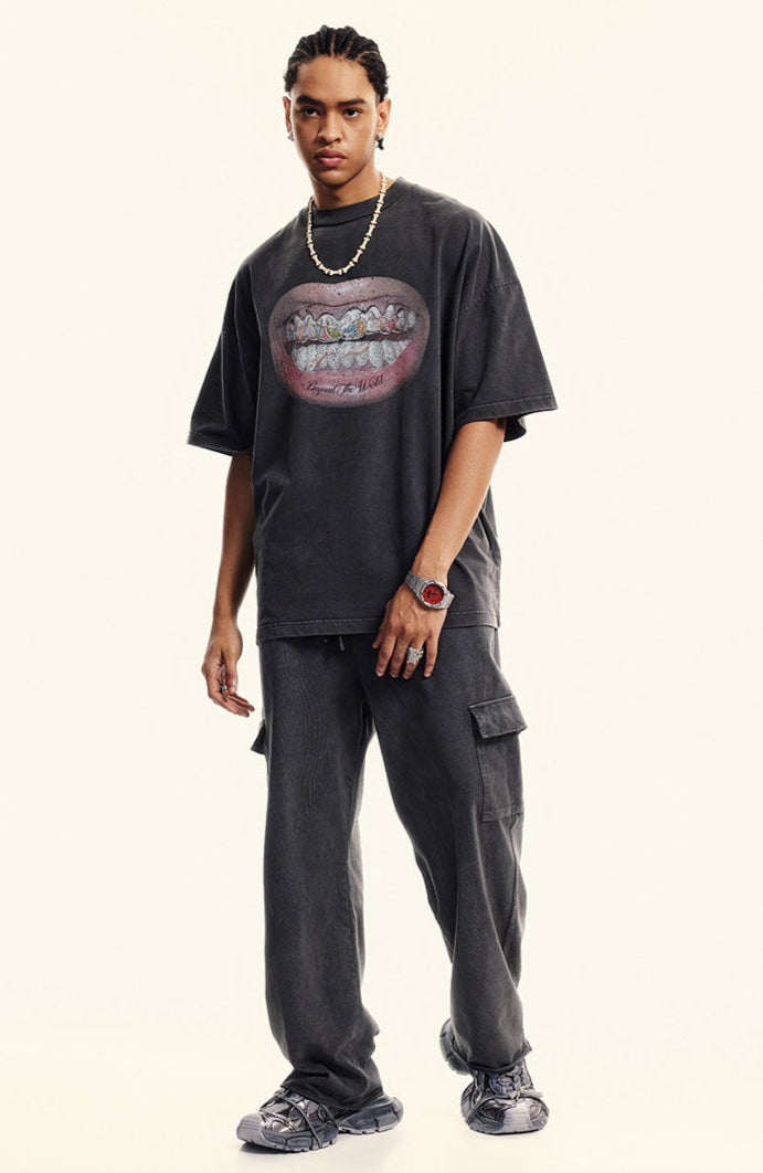 Model standing in black oversized T-shirt featuring surreal open-mouth grill design