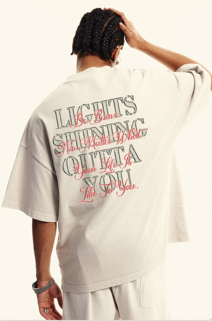 Back of off-white tee with layered street-style typography reading 'Lights Shining Outta You.