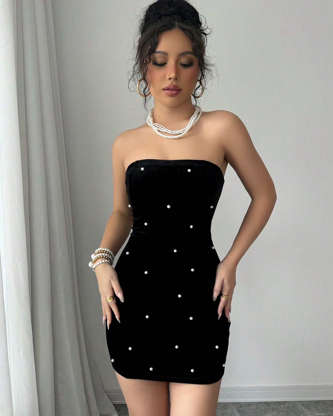 Front view of black velvet bodycon mini dress with scattered pearls and strapless design.