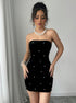 Front view of black velvet bodycon mini dress with scattered pearls and strapless design.