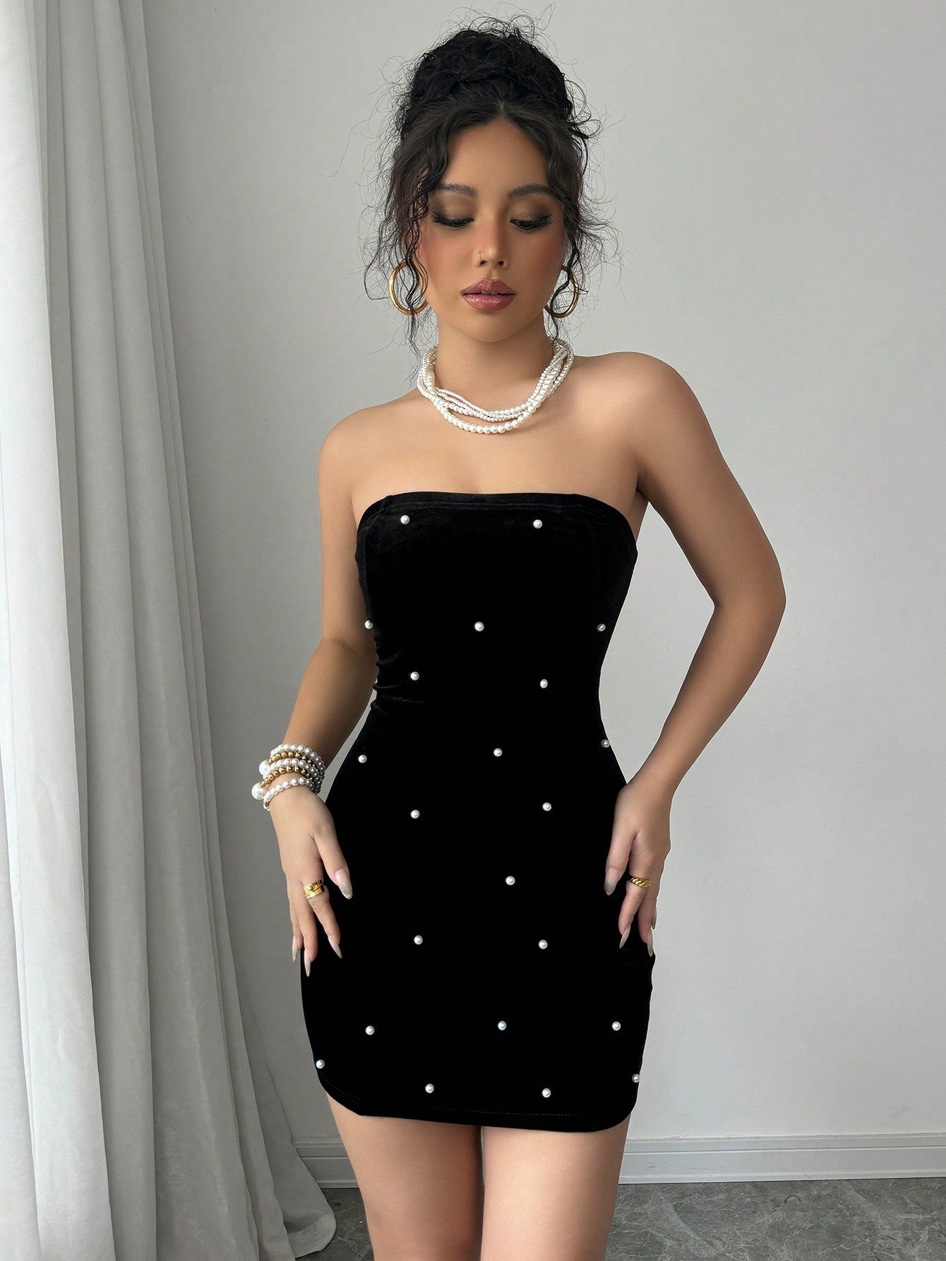 Front view of black velvet bodycon mini dress with scattered pearls and strapless design.