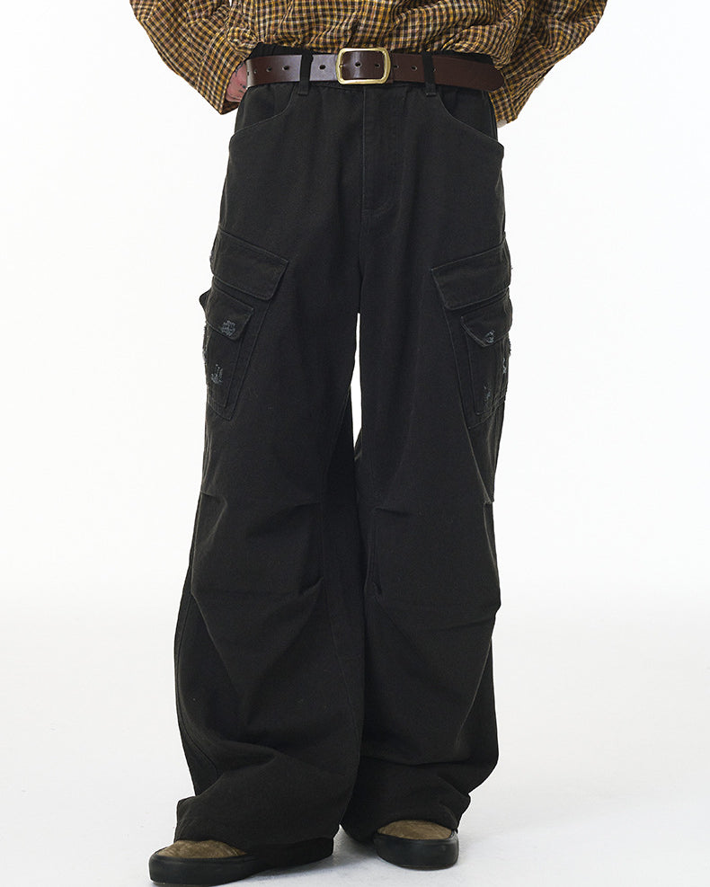 Person wearing black cargo pants and a patterned shirt on a white background