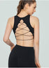 Woman wearing black cross-back sports bra and leggings, back view showing lace-up detail.
