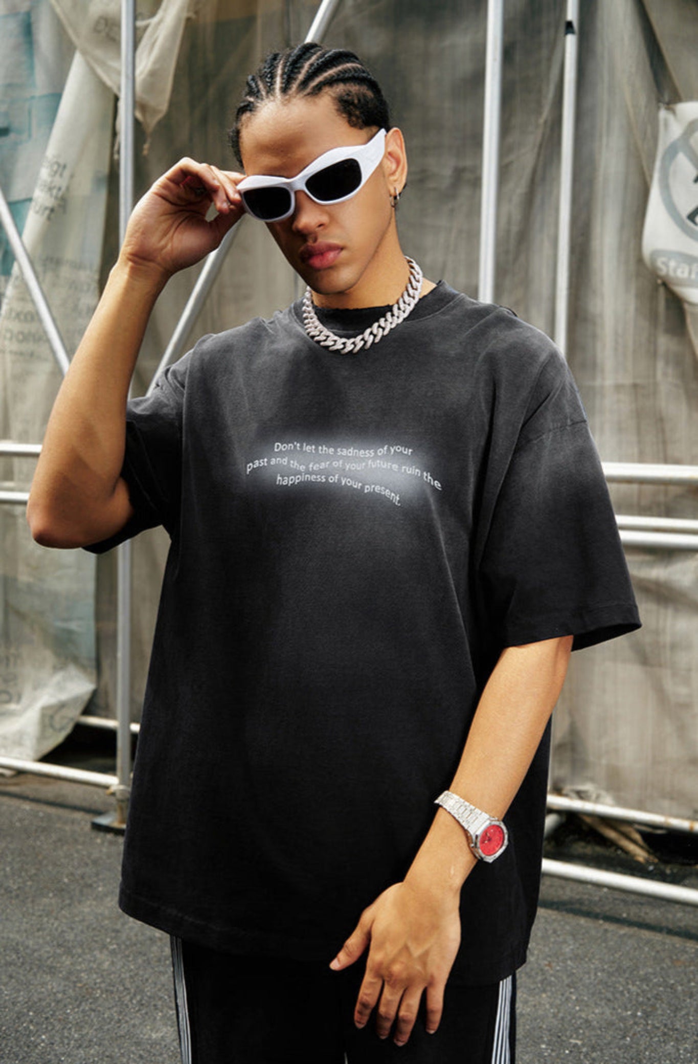 Close-up of man wearing black quote tee, white sunglasses, and thick silver chain.