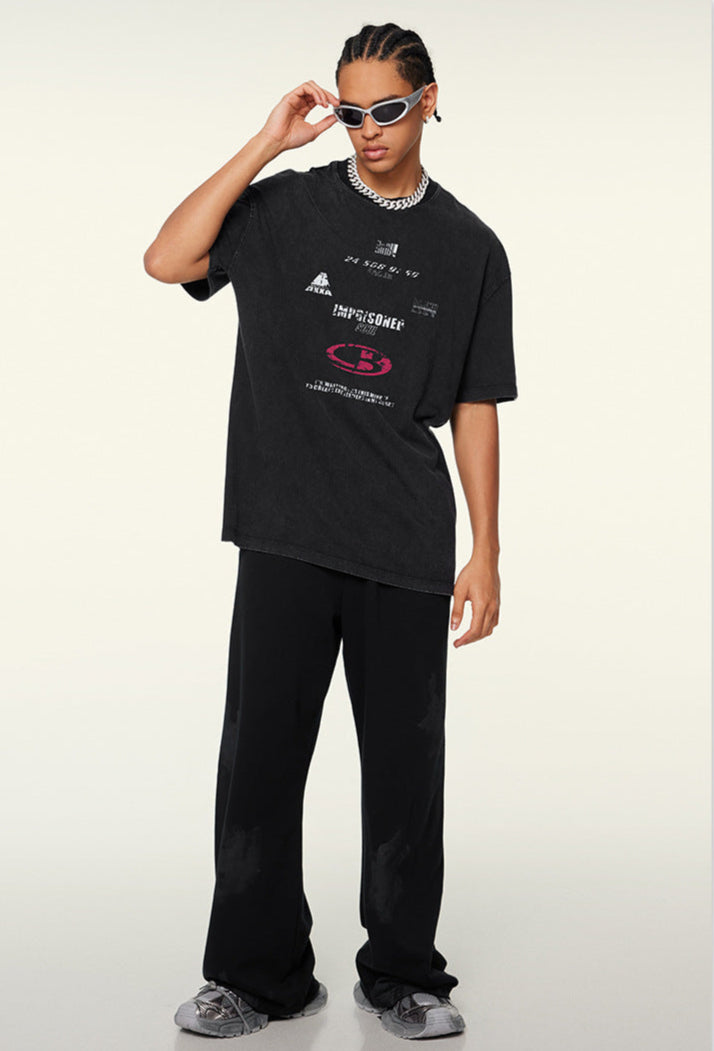 Model wears black graphic tee with sunglasses and wide-leg pants