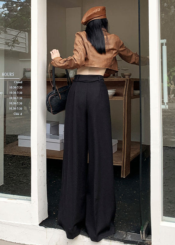 Back view of black drawstring trousers paired with cropped brown jacket and shoulder bag.