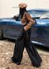 Side profile of model walking in black wide-leg trousers with high waist and soft drape.