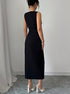 Back view of woman wearing a black sleeveless slit dress against a plain background